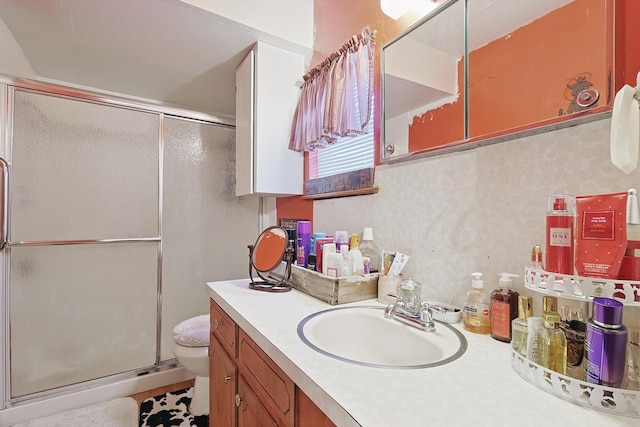 bathroom featuring vanity, a shower with shower door, and toilet