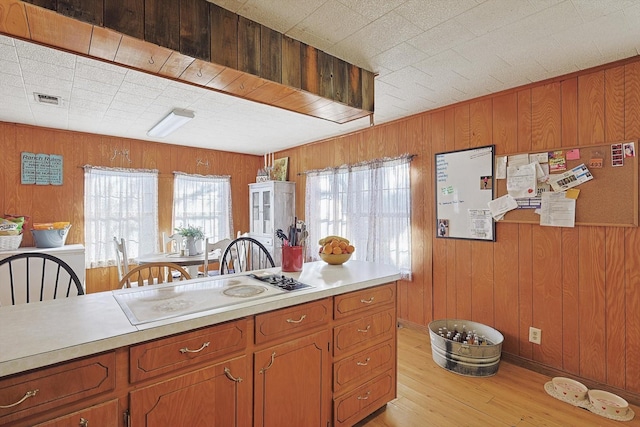 kitchen with white cooktop, light hardwood / wood-style floors, and wood walls