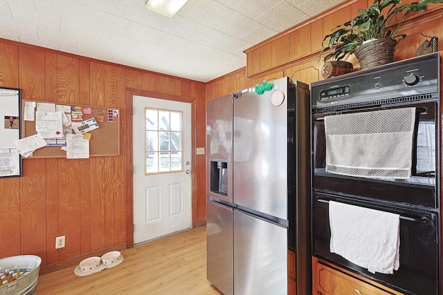 kitchen featuring stainless steel fridge and wooden walls