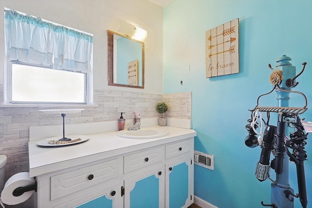 bathroom featuring vanity, decorative backsplash, and toilet