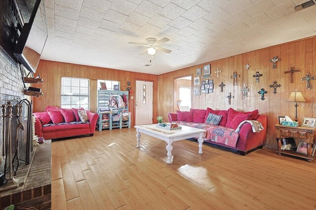 living room with hardwood / wood-style flooring, ceiling fan, and wooden walls