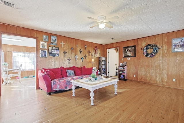 living room with ceiling fan, hardwood / wood-style floors, and wood walls