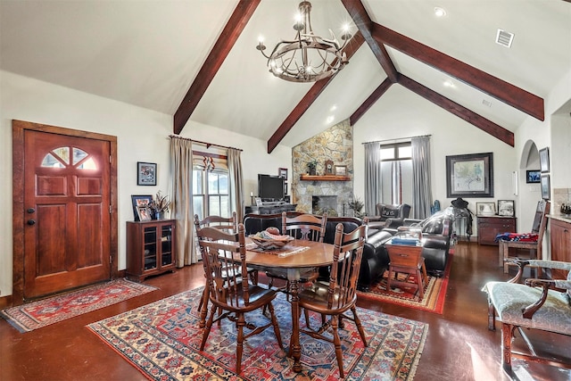 dining area featuring beam ceiling, a stone fireplace, high vaulted ceiling, and a chandelier