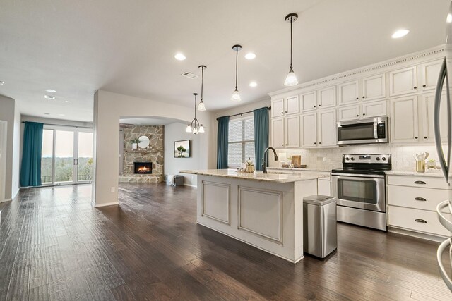 kitchen with dark wood-type flooring, tasteful backsplash, open floor plan, stainless steel appliances, and a fireplace