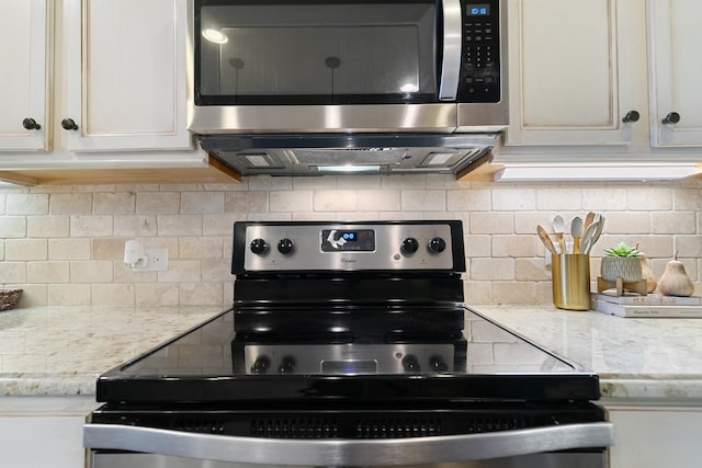 kitchen featuring light stone countertops, electric range, white cabinets, stainless steel microwave, and tasteful backsplash