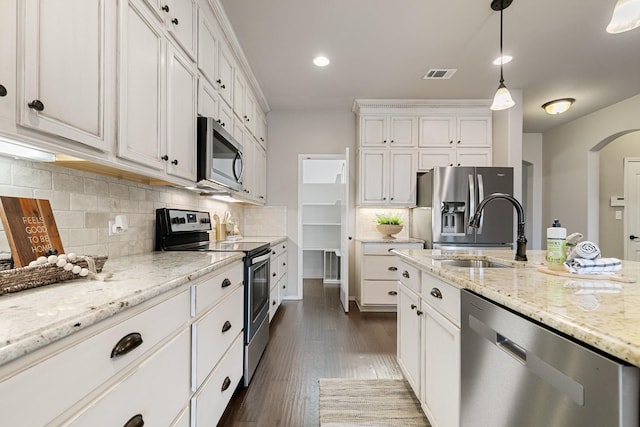 kitchen with visible vents, arched walkways, a sink, stainless steel appliances, and white cabinets