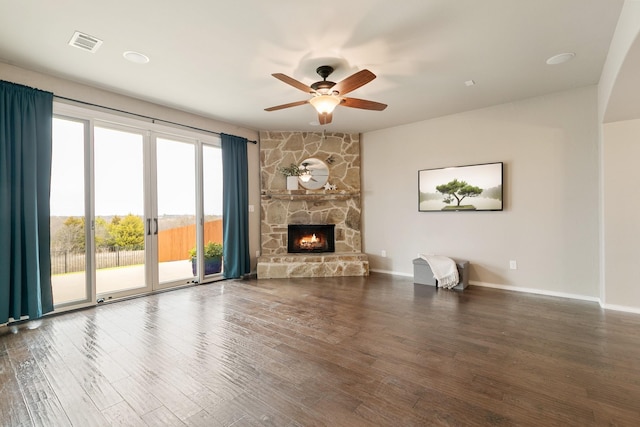 unfurnished living room with a ceiling fan, wood finished floors, visible vents, baseboards, and a stone fireplace