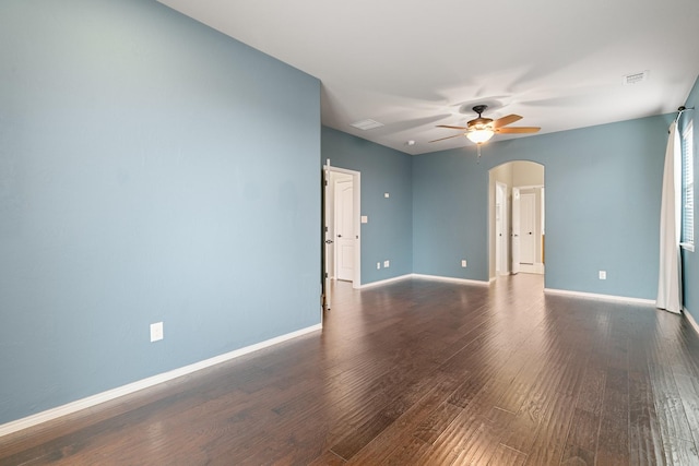 empty room with visible vents, a ceiling fan, wood finished floors, arched walkways, and baseboards