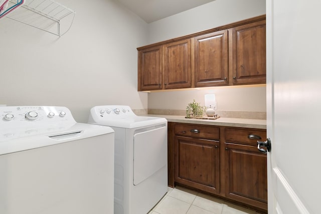 washroom with washing machine and dryer, light tile patterned floors, and cabinet space