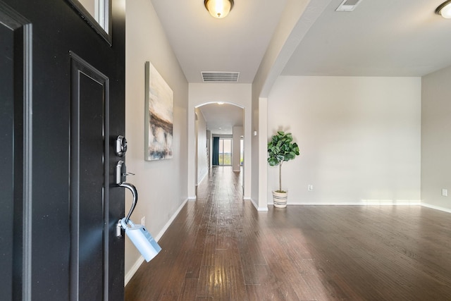 entrance foyer with wood finished floors, arched walkways, visible vents, and baseboards