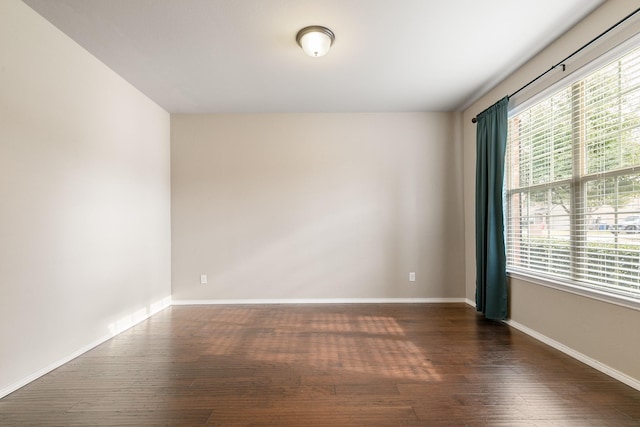 empty room with dark wood-style floors, baseboards, and a healthy amount of sunlight