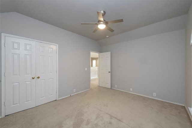 unfurnished bedroom with ceiling fan, a closet, light colored carpet, and lofted ceiling