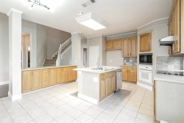 kitchen with black microwave, sink, dishwasher, tasteful backsplash, and a kitchen island with sink