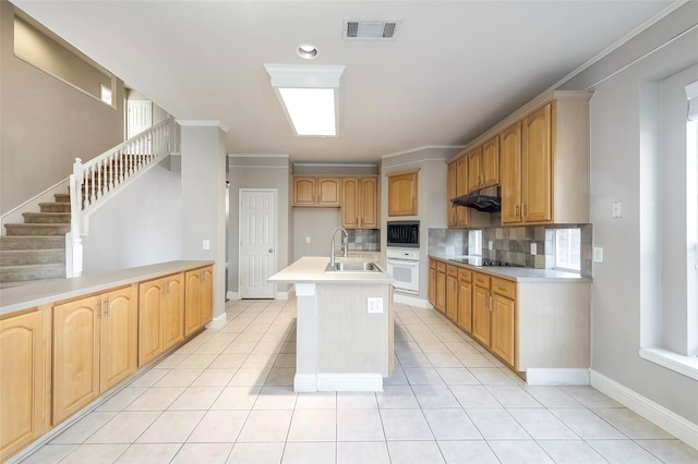 kitchen with sink, an island with sink, decorative backsplash, black appliances, and ornamental molding