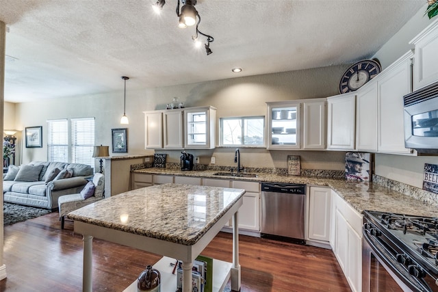 kitchen featuring white cabinets, sink, dishwasher, a center island, and hanging light fixtures