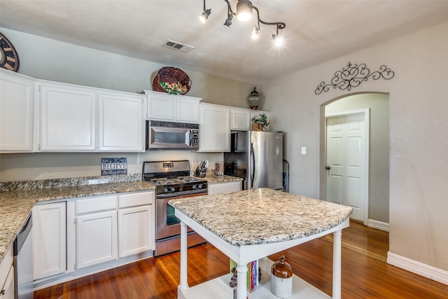 kitchen featuring white cabinets, dark hardwood / wood-style floors, light stone counters, and stainless steel appliances