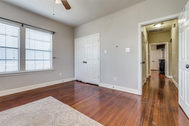 unfurnished bedroom with a closet, dark wood-type flooring, and ceiling fan