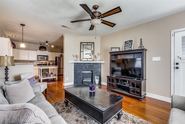 living room featuring ceiling fan, a fireplace, and hardwood / wood-style flooring