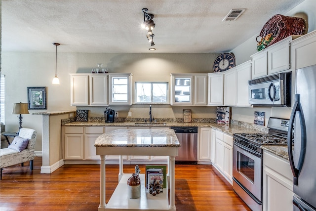 kitchen featuring white cabinets, decorative light fixtures, sink, and stainless steel appliances