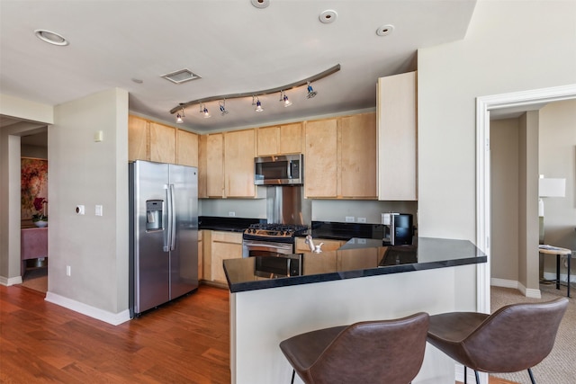 kitchen featuring kitchen peninsula, light brown cabinetry, stainless steel appliances, and dark hardwood / wood-style floors