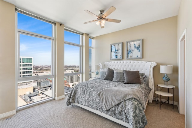 bedroom with expansive windows, ceiling fan, carpet floors, and multiple windows