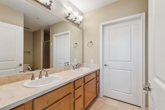 bathroom with tile patterned flooring, vanity, a shower with door, and toilet