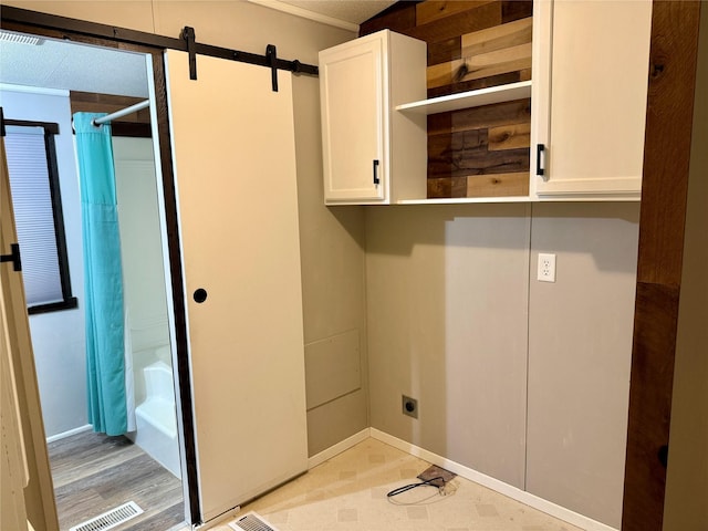 laundry area featuring electric dryer hookup, a barn door, and cabinets