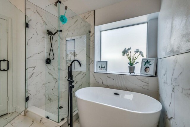 bathroom featuring plenty of natural light, separate shower and tub, and tile walls