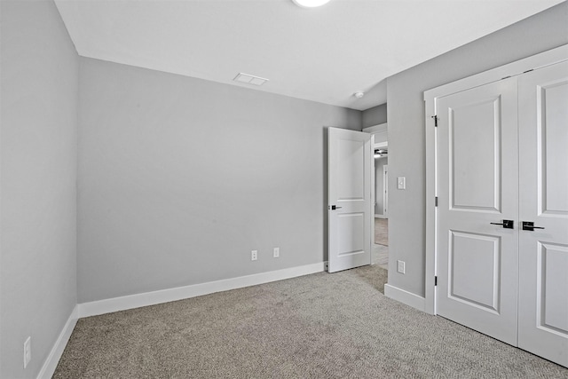 unfurnished bedroom with light colored carpet and a closet