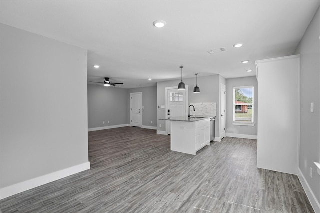 kitchen with ceiling fan, a kitchen island with sink, sink, decorative light fixtures, and white cabinets