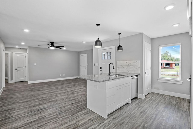 kitchen with dishwasher, white cabinets, sink, hanging light fixtures, and light stone counters