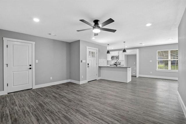 unfurnished living room featuring dark hardwood / wood-style floors and ceiling fan