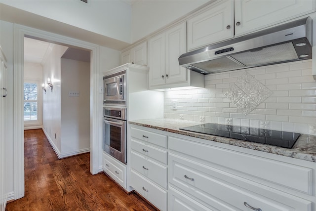 kitchen with dark wood-type flooring, light stone counters, backsplash, white cabinets, and appliances with stainless steel finishes