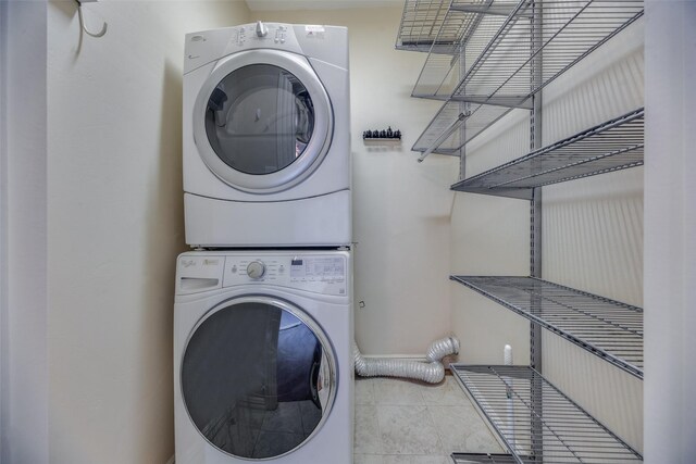 laundry room with tile patterned flooring and stacked washing maching and dryer