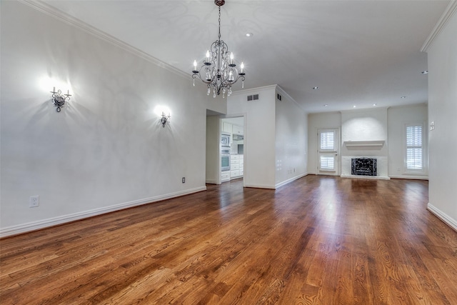 unfurnished living room featuring hardwood / wood-style floors, a notable chandelier, crown molding, and a fireplace