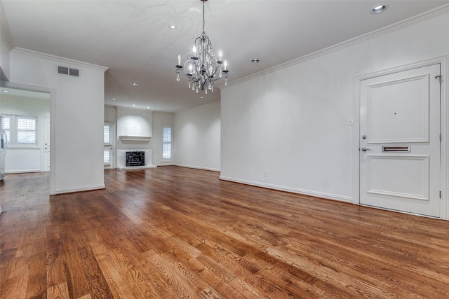 unfurnished living room featuring a chandelier, wood-type flooring, and ornamental molding