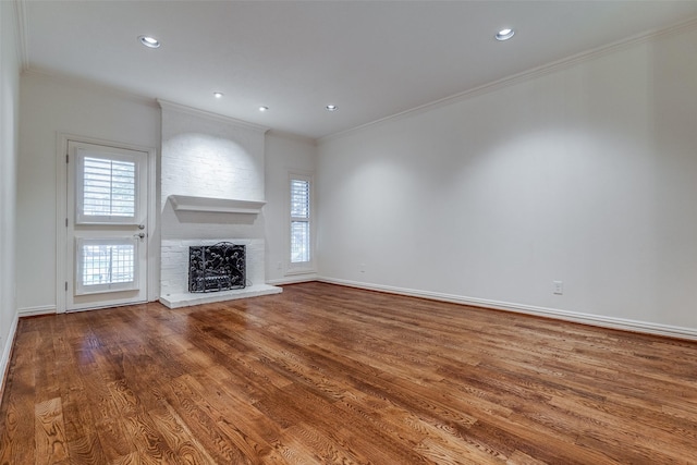 unfurnished living room featuring a brick fireplace, hardwood / wood-style floors, and ornamental molding