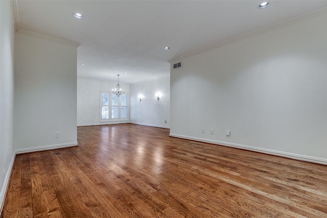 spare room featuring wood-type flooring, an inviting chandelier, and ornamental molding