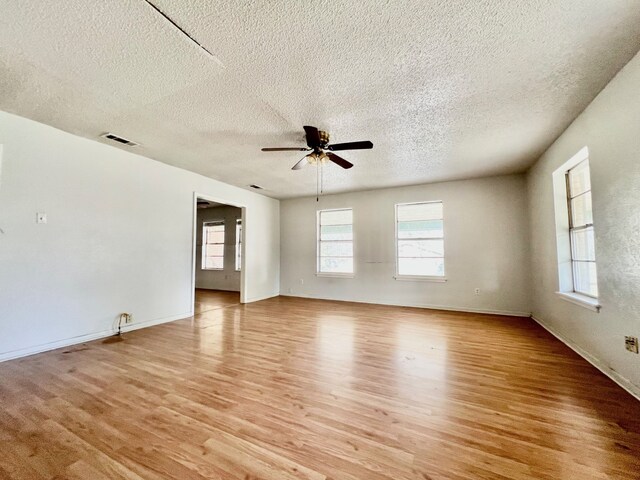 empty room with ceiling fan, a textured ceiling, and light wood-type flooring