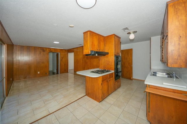 kitchen with kitchen peninsula, gas stovetop, sink, oven, and wood walls