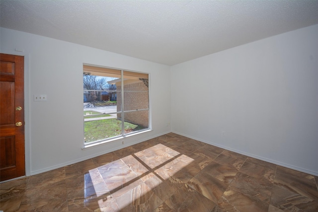 spare room featuring a textured ceiling and a healthy amount of sunlight