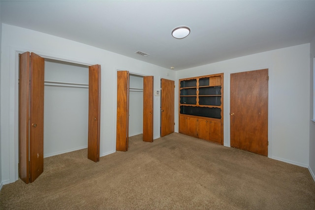 unfurnished bedroom with light carpet and two closets