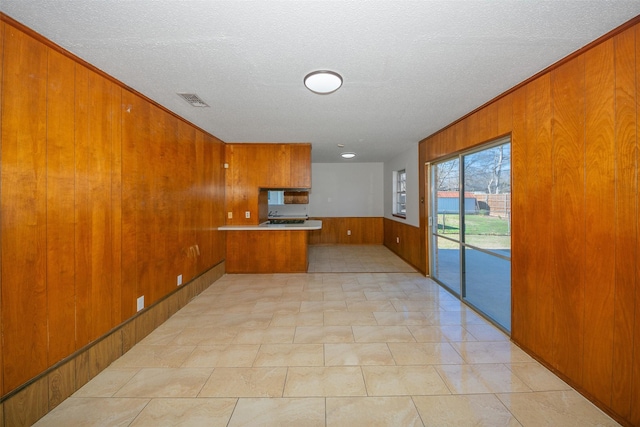 kitchen with kitchen peninsula, a textured ceiling, and wood walls