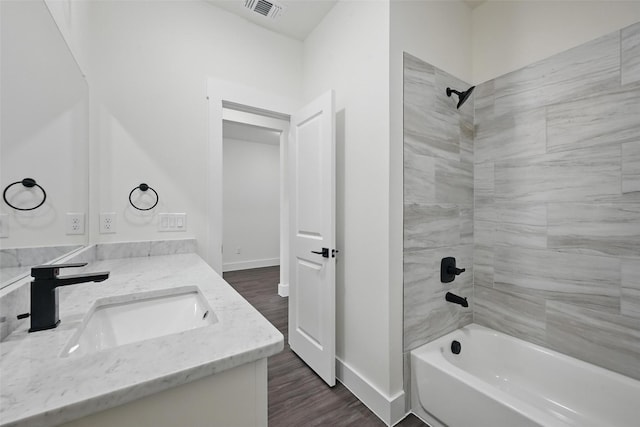 bathroom featuring vanity, wood finished floors, baseboards, tub / shower combination, and visible vents