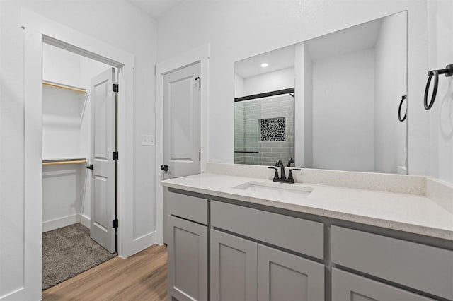 bathroom with hardwood / wood-style flooring, vanity, and a shower with shower door