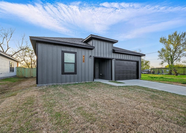 view of front of property featuring fence, an attached garage, board and batten siding, driveway, and a front lawn