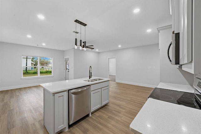 kitchen with hanging light fixtures, sink, an island with sink, appliances with stainless steel finishes, and white cabinetry