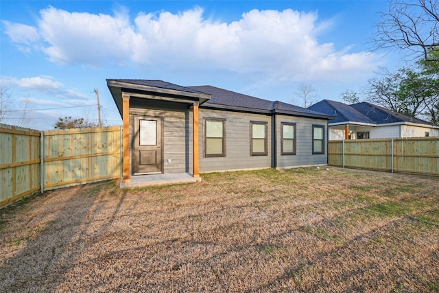 back of property with a fenced backyard and a yard
