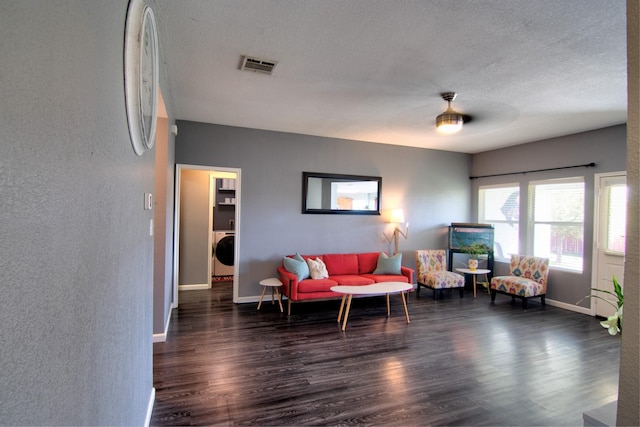 living room with washer / clothes dryer, ceiling fan, dark hardwood / wood-style flooring, and a textured ceiling