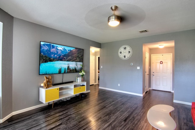 living room featuring ceiling fan, dark wood-type flooring, and a textured ceiling